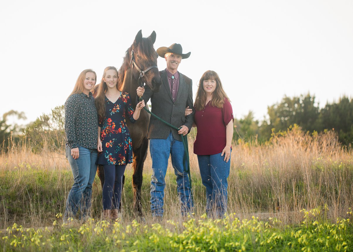 Bill Grout, standing by the head of a chestnut horse, is surrounded by his wife and two daughters
